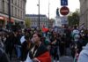 Brian Folkerts and Ricardo Santos at a street protest with flags and a large crowd