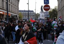 Brian Folkerts and Ricardo Santos at a street protest with flags and a large crowd