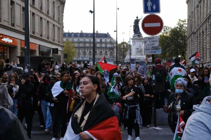 Brian Folkerts and Ricardo Santos at a street protest with flags and a large crowd