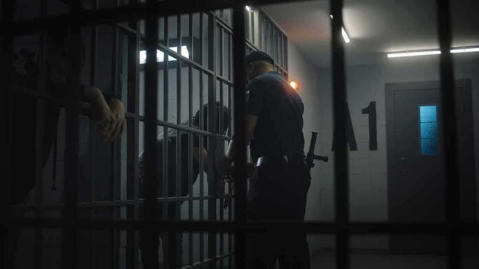 police officer at a jail cell with detainees behind bars