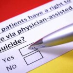 Doctor-Led Death LEGALIZED Fulfilling Woke PM’s Wish Hand holding pen over a yes or no checkbox on a medical ethics question