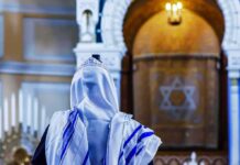 Yom Kippur Gunfire Stuns Synagogue Person in white and blue prayer shawl facing ornate interior