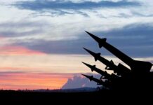 Silhouetted missiles on launchers against a colorful sunset sky