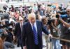 Donald Trump walks up steps through a crowd as A. J. Calloway films nearby