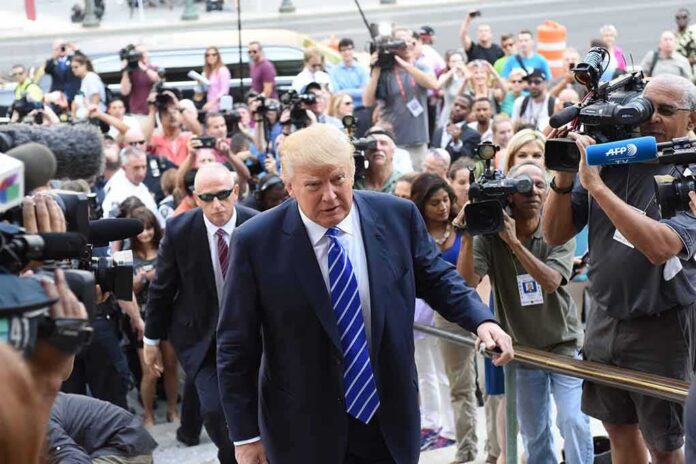 Donald Trump walks up steps through a crowd as A. J. Calloway films nearby