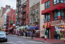 Backlash Erupts Over El-Sayed’s Racist Jab City street with brick buildings, fire escapes, and busy storefronts
