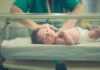 Newborn baby in hospital bassinet being cared for by nurse