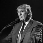 Donald Trump speaking at a microphone in a black-and-white photo