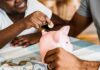Child placing coin into pink piggy bank