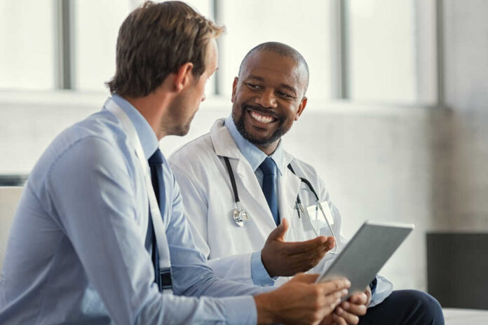 Two,Mature,Smiling,Doctors,Having,Discussion,About,Patient,Diagnosis,,Holding